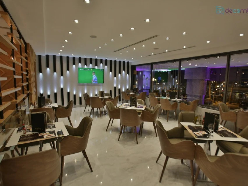 Restaurant lounge de nuit avec éclairage dramatique, mur cannelé et vue sur la ville